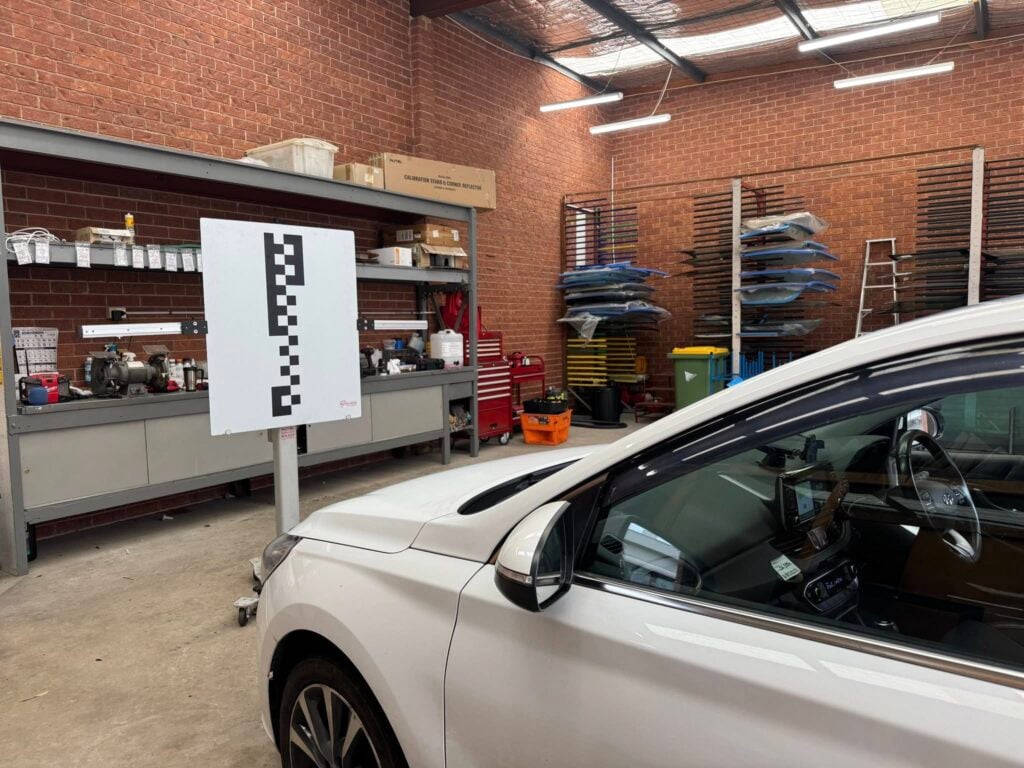 White car in workshop during windscreen calibration at Gosford Windscreens.