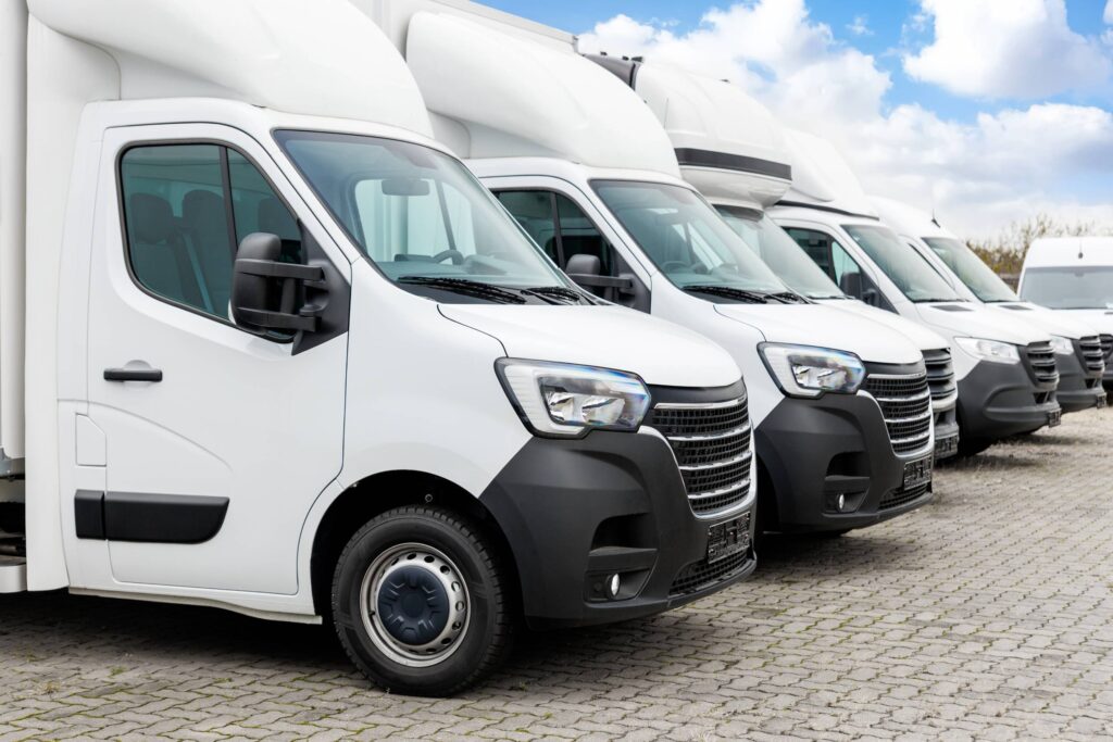 Row of white service vans parked on paved lot at Gosford Windscreens.