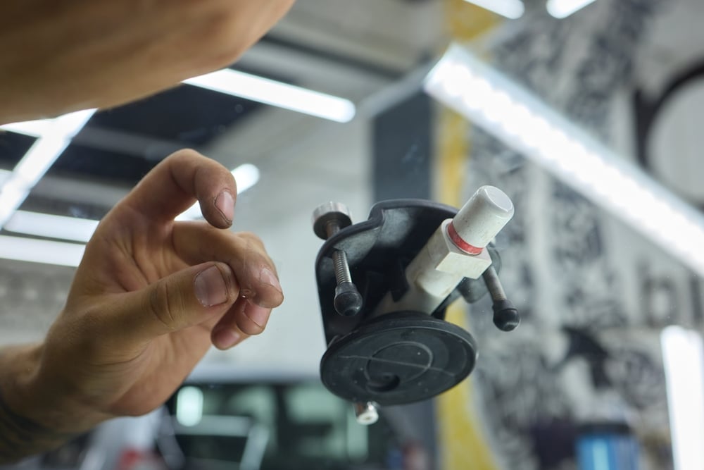Technician repairing a chipped car windscreen using resin tool at Gosford Windscreens.
